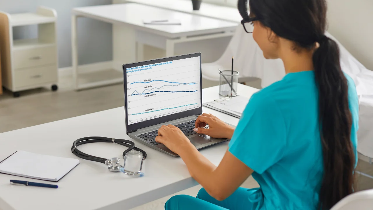 Profesional de la salud investigando en una laptop con gráficos de datos sobre tendencias en salud.