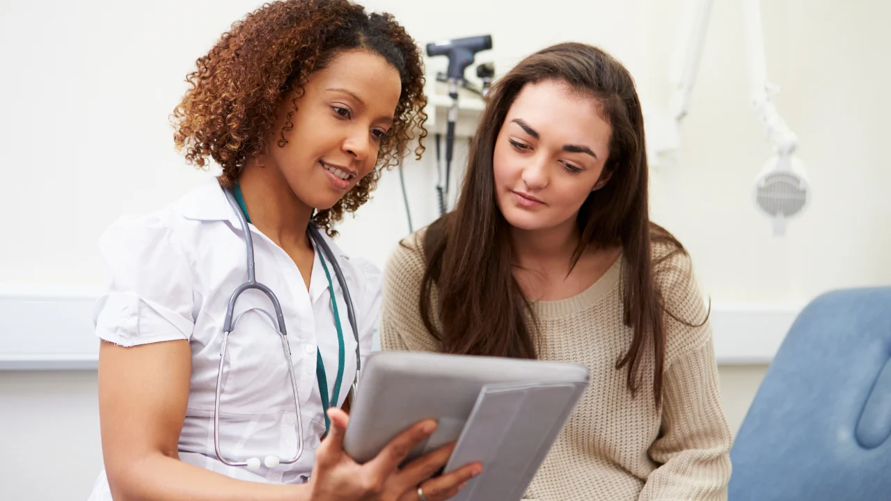 Un médico interactuando con una pantalla táctil mostrando datos de pacientes.
